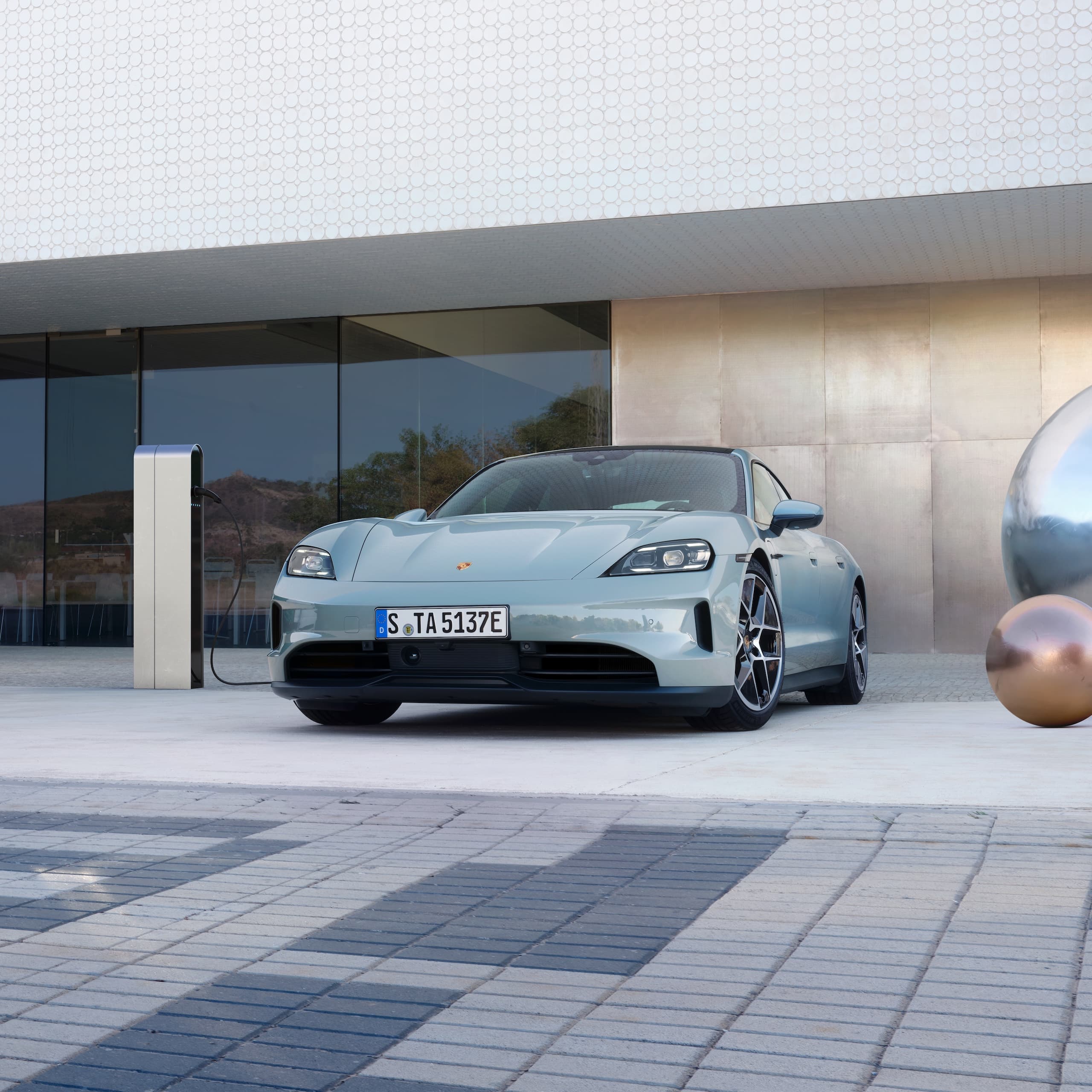 En Porsche Taycan parkerte utenfor foran en moderne bygning.